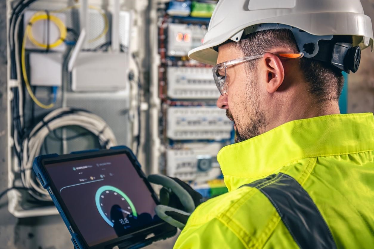 Electrician doing maintenance while using an app on a tablet